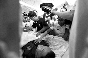 28日，兇手門多薩身著警服躺在棺木里。
